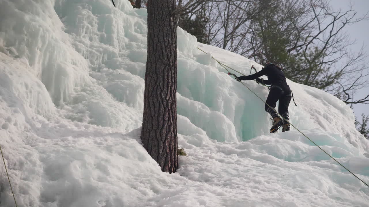 una mujer escalando en hielo su camino hacia una montaña cubierta de nieve y hielo