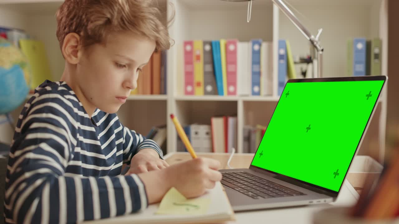 el niño inteligente usa una computadora portátil de pantalla verde para aprender, escribe información útil. aprendizaje a distancia, educación electrónica, concepto de aprendizaje electrónico