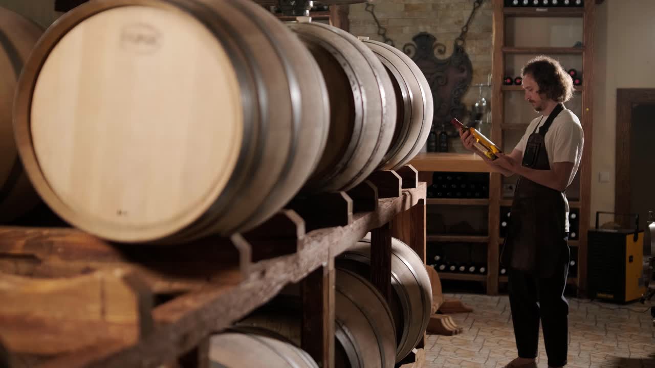 성공한 남성 소멜리어의 진정한 은 맛을 맛보고 와인 지하실에서 투명한 유리통에 부어 놓은 화이트 와인의 품질을 확인하는 것입니다.