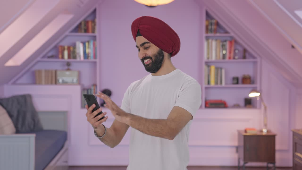 Uomo indiano Sikh felice che scorre il telefono.