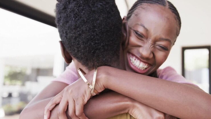 un couple afro-américain heureux souriant et s'embrassant dans le salon, au ralenti.