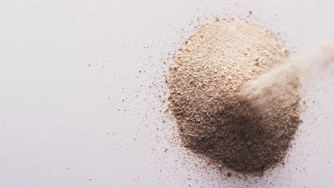 Video-of-close-up-of-sand-grains-pouring-into-heap-and-copy-space-on-white-background