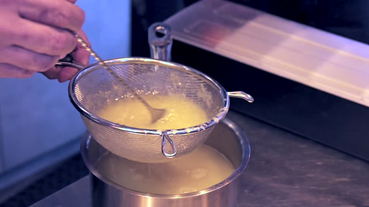 Close up side view of bartender stirring lemon juice in a colander, Slow motion 100fps