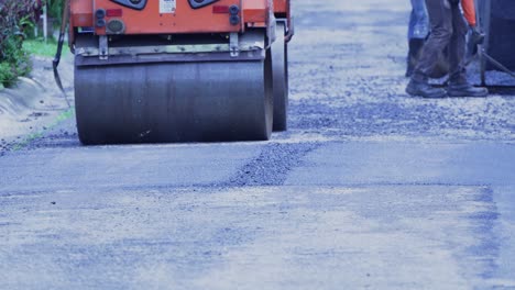 Stadtarbeiter-Und-Kleine-Dampfwalze,-Die-Asphalt-Auf-Der-Straße-Befestigen