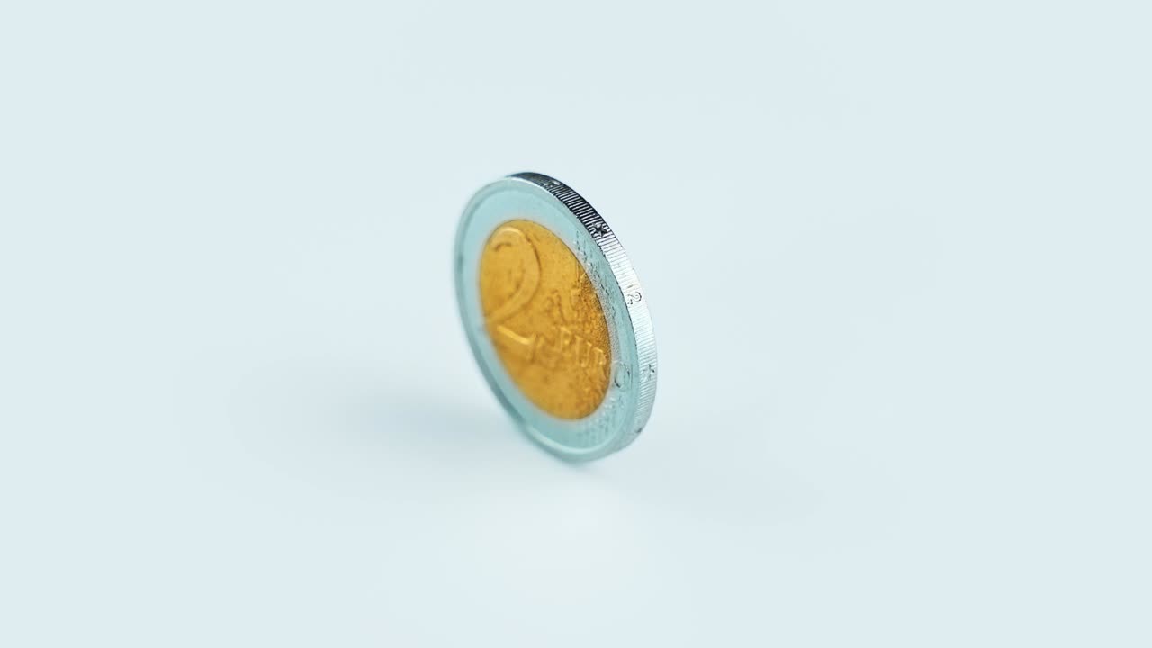 la moneda de dos euros brillante gira a la luz brillante sobre el blanco