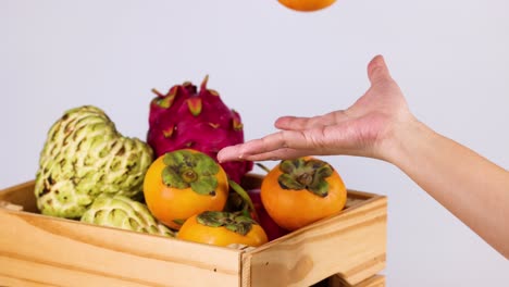 hands interacting with various fruits in crate