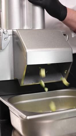 chef using a commercial vegetable slicer to cut zucchini