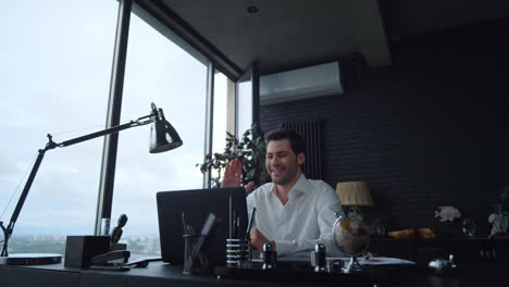 Positive-businessman-talking-with-business-partner-during-video-chat-in-office