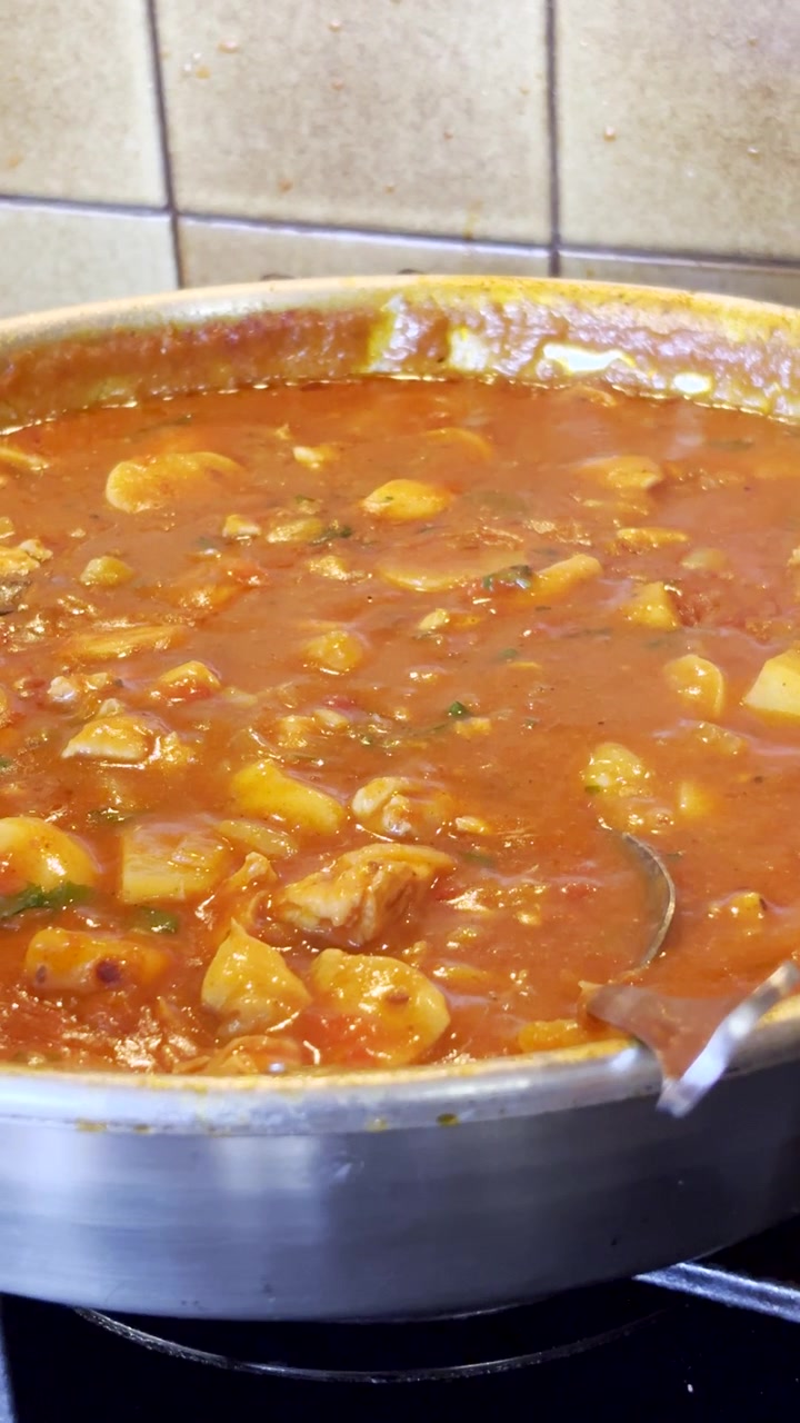 Ensopado de frango picante com curry cozido lentamente em panela de aço inoxidável no fogão. Vertical.