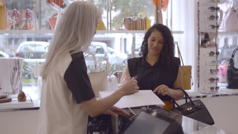 cheerful latin woman paying for purchase new clothes