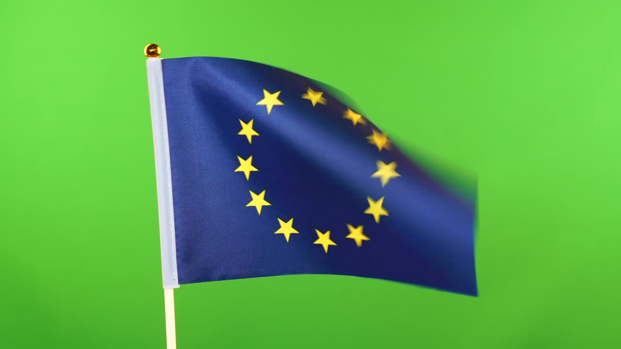 Flag of EU on flagpole on green background. European Union Flag waving in wind.