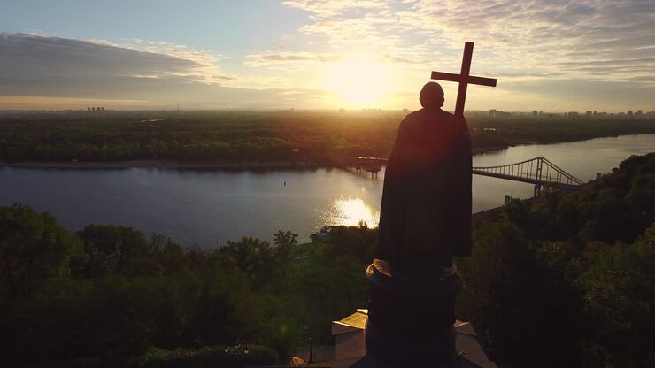 Silhouette Prince Vladimir with christian cross in Kiev city on sunset landscape