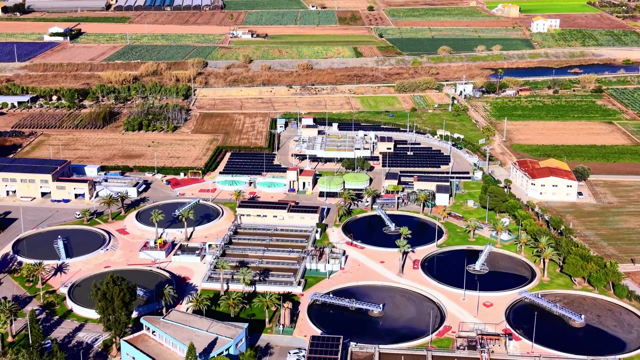 Aerial view of industrial clarifier tanks and rows of photovoltaic panels at a sustainable treatment facility. Modern water purification system with solar panel arrays