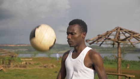 slow motion close up shot of a young african mans face as he does kick ups on a stormy beach in africa