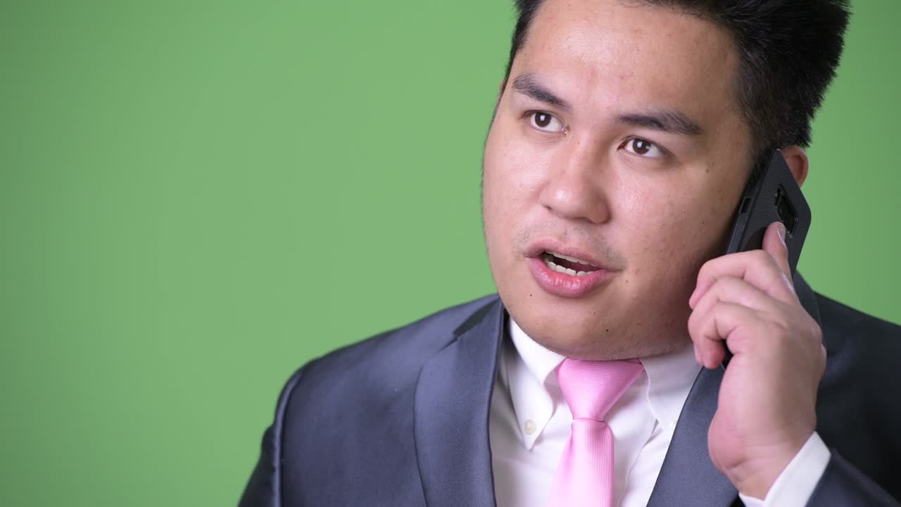 초록색 배경에 젊은 잘생긴 과체중 아시아 사업가