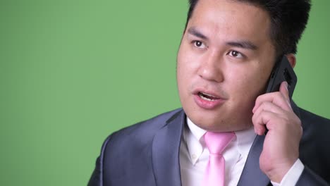 joven apuesto hombre de negocios asiático con sobrepeso contra un fondo verde