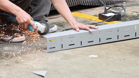 worker using grinder to cut metal piece