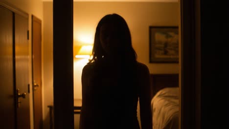 a mysterious silhouette in a dimly lit bedroom: exploring the intrigue of shadows and light as a figure enters and exits the frame