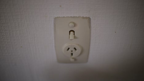 caucasian hand unplugging white plug then turning off power point switch