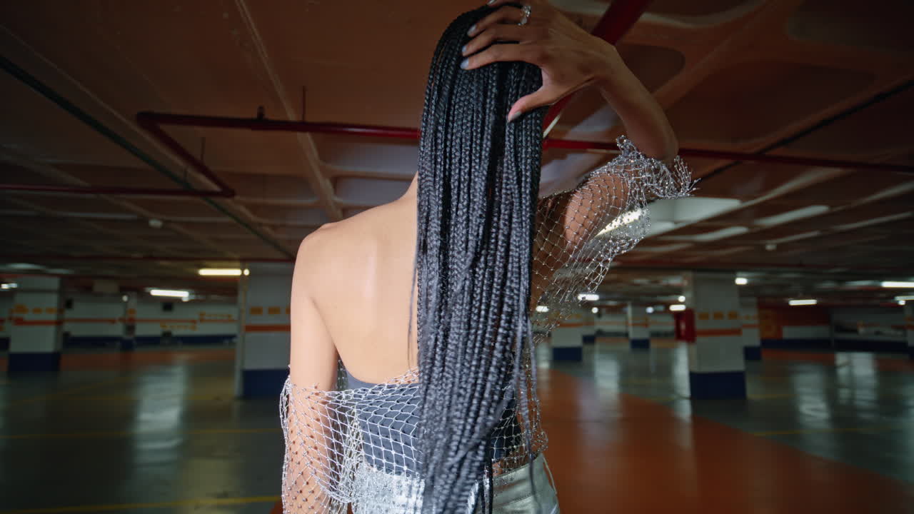 dreadlocks mujer girando la cámara tocando el cabello espacio oscuro vista trasera. chica posando