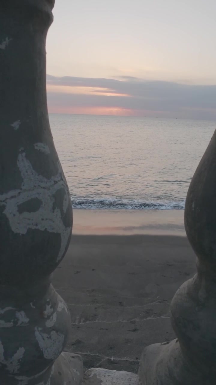 Vista delle onde dell'oceano al tramonto attraverso una balaustra in pietra