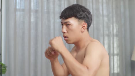 close up of asian teenager boy boxing warm up while doing shirtless workout at home