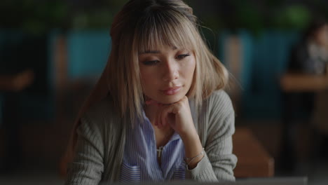 portrait of a beautiful young and attractive asian woman is sitting and looks worried and serious as she broods in front of her laptop computer during the day.