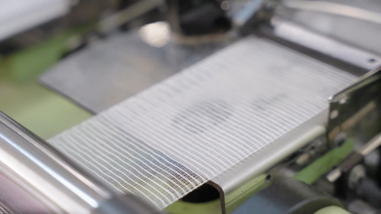 Close-up of a loom machine in action, showcasing threads, moving parts, and the weaving process, ideal for textile manufacturing, craftsmanship, industrial production, and machinery visuals