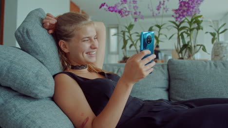 young woman relaxing on couch and using smartphone