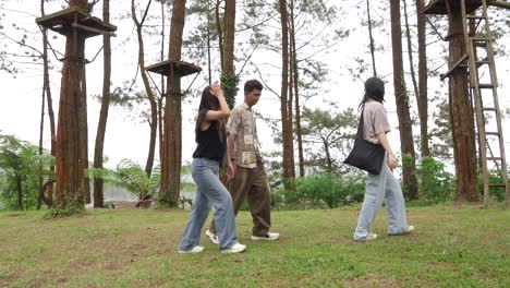 young asian friends walking on forest footpath in nature