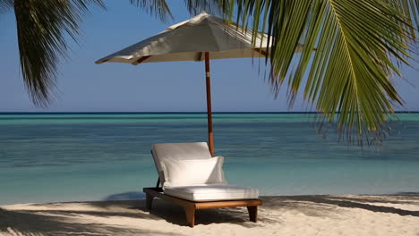 a serene tropical beach with a lounge chair and umbrella by the turquoise ocean