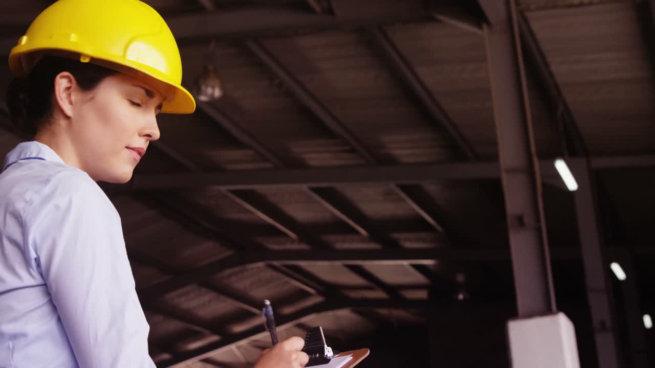 Female supervisor maintaining record on clipboard