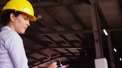 Female-supervisor-maintaining-record-on-clipboard