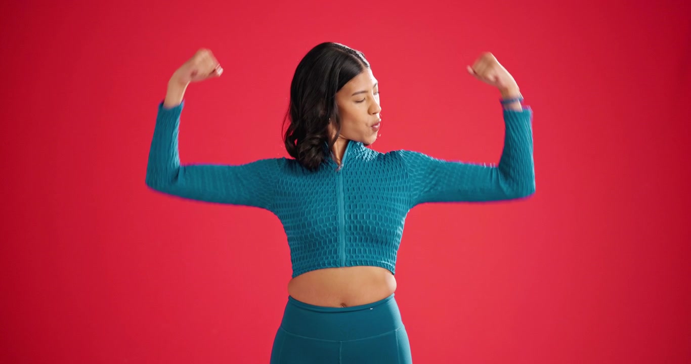 Fit Woman Flexing Her Biceps Against a Red Background