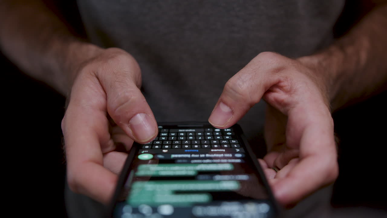 joven sosteniendo un teléfono móvil de cerca, usándolo para escribir y enviar mensajes