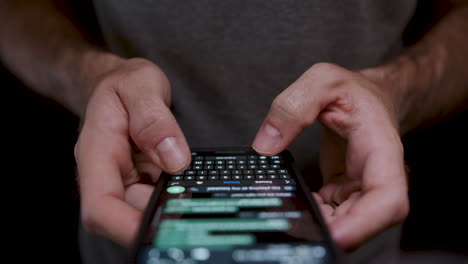 young man holding a mobile phone close up, using it to write and send messages