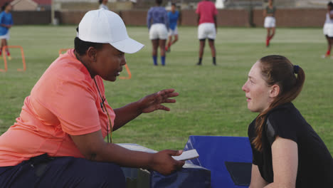 Young-adult-female-rugby-player-and-coach-at-training