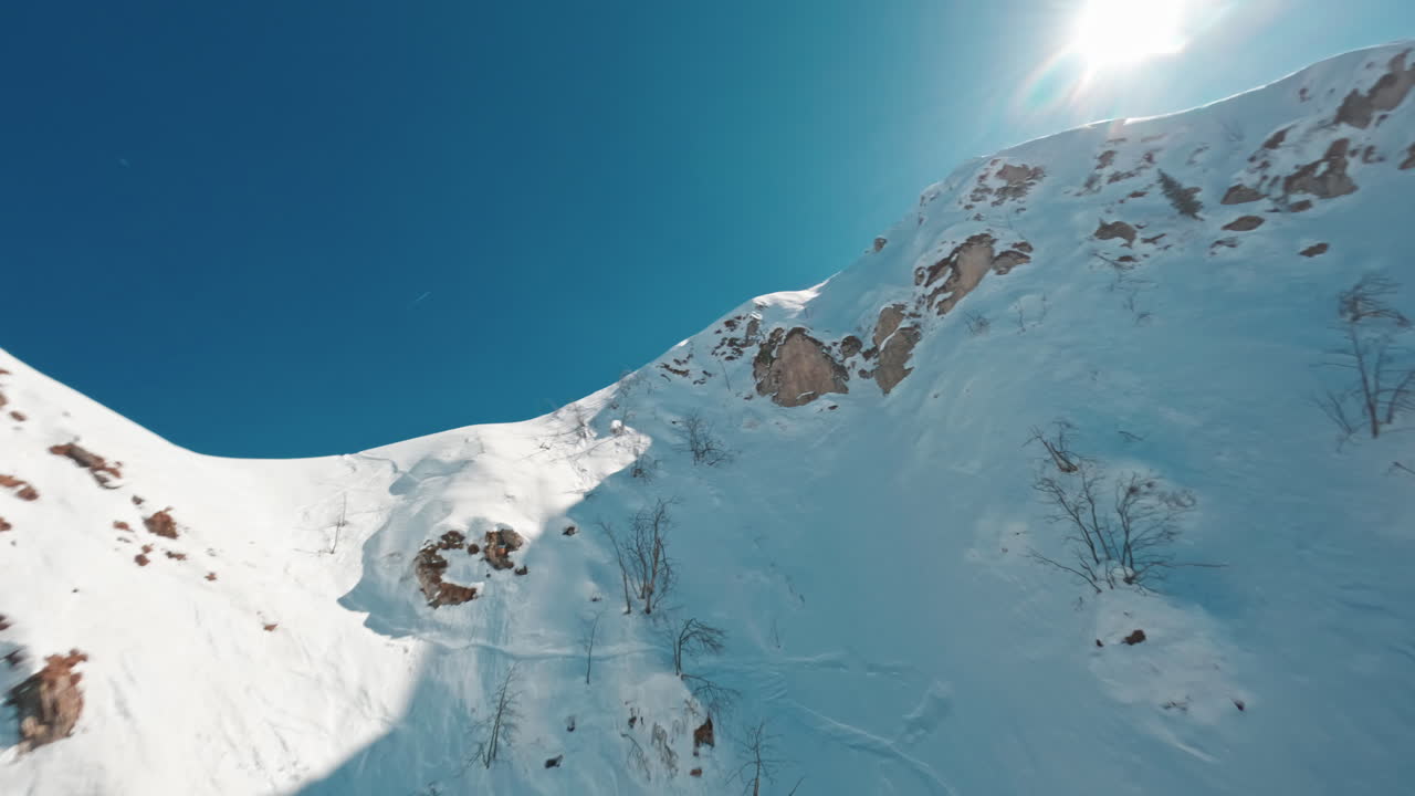Snow-covered mountain peak under a bright blue sky captured from a low angle