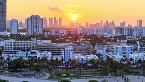 aerial pan left view of buildings on the south beach coast in miami, florida, united states. skyline with buildings at sunset with clear sky and the sun.