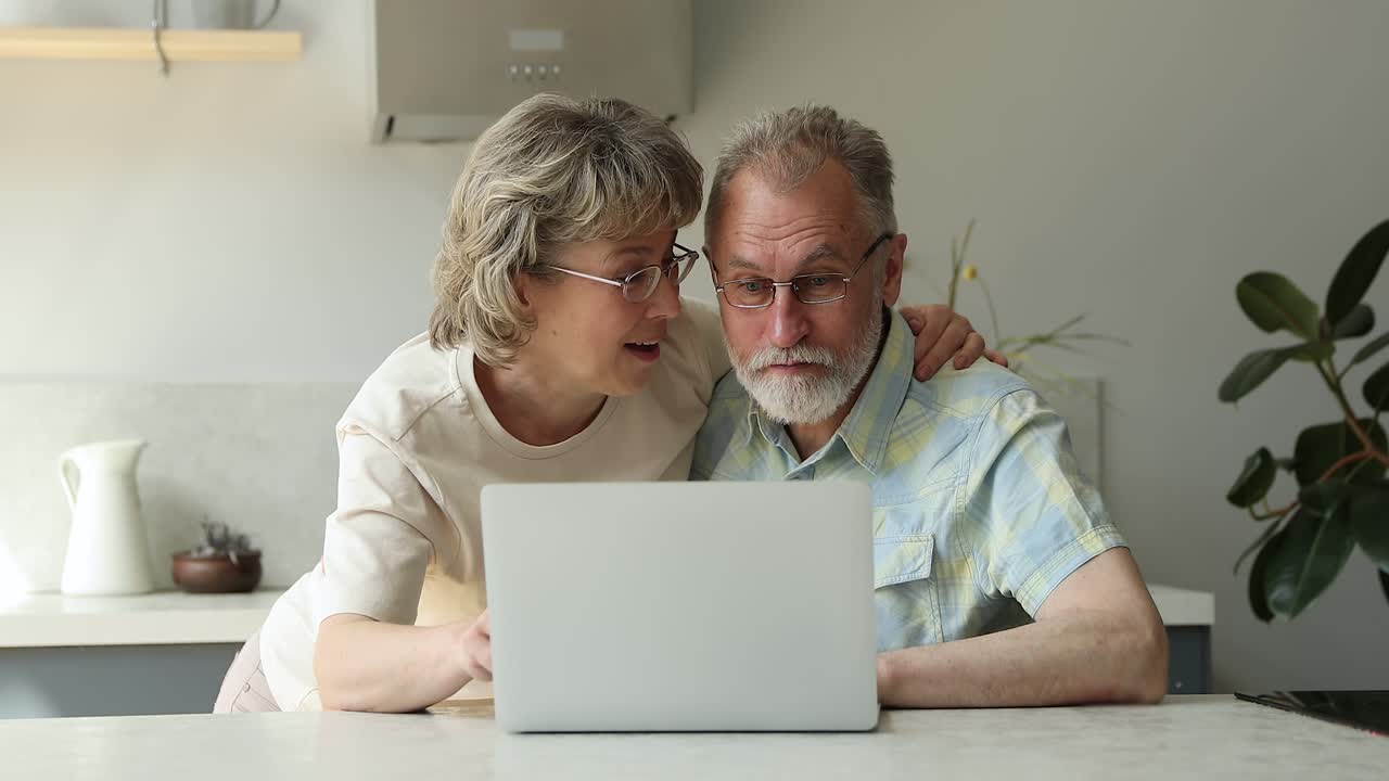 Overjoyed senior couple laugh hug before pc screen winning game