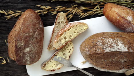 Eine-Nahaufnahme-Von-Oben-Auf-Frisch-Gebackene-Traditionelle-Italienische-Ciabatta-Brote,-Die-Auf-Einem-Holztisch-Zubereitet-Und-In-Scheiben-Geschnitten-Werden,-Um-Serviert-Zu-Werden