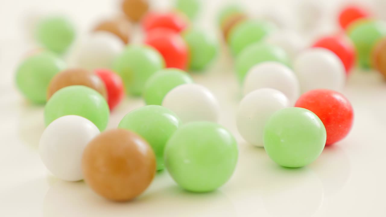 caramelos coloridos en forma de botón en superficie reflectante blanca 4k