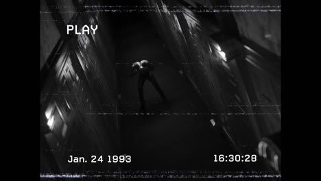 animación de pantalla de reproducción en blanco y negro que muestra una figura en un pasillo oscuro sosteniendo la cabeza con dolor