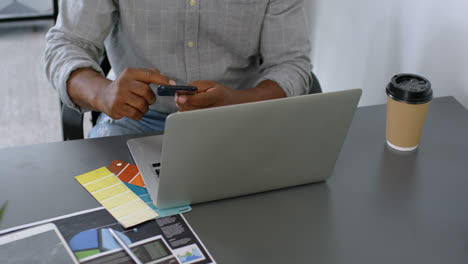 Man-having-coffee-while-using-mobile-phone-on-desk-4k