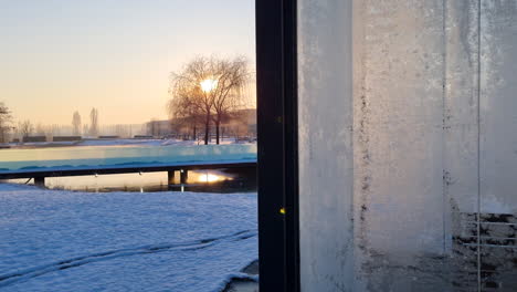 glass cabin and frozen lake at sunrise on a cold winter morning