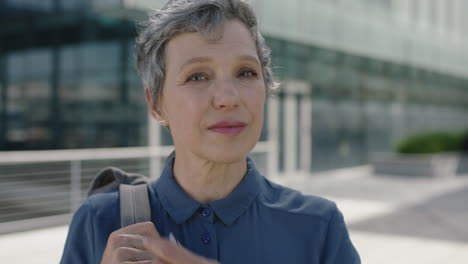 portrait-of-mature-business-woman-removes-earphones-looking-pensive-at-camera-in-urban-background