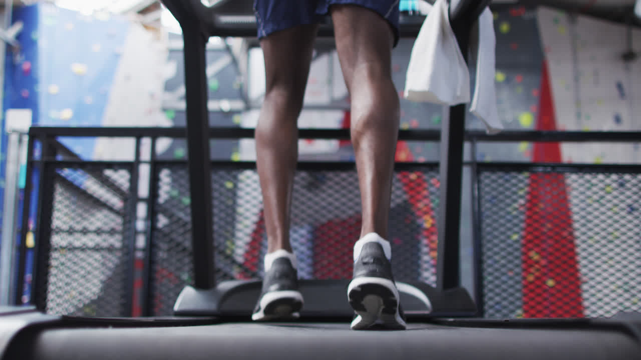 Low section of fit african american man running on treadmill in the gym