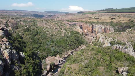 volando por encima de un barranco rocoso hacia una pintoresca cascada que se sumerge en el desfiladero