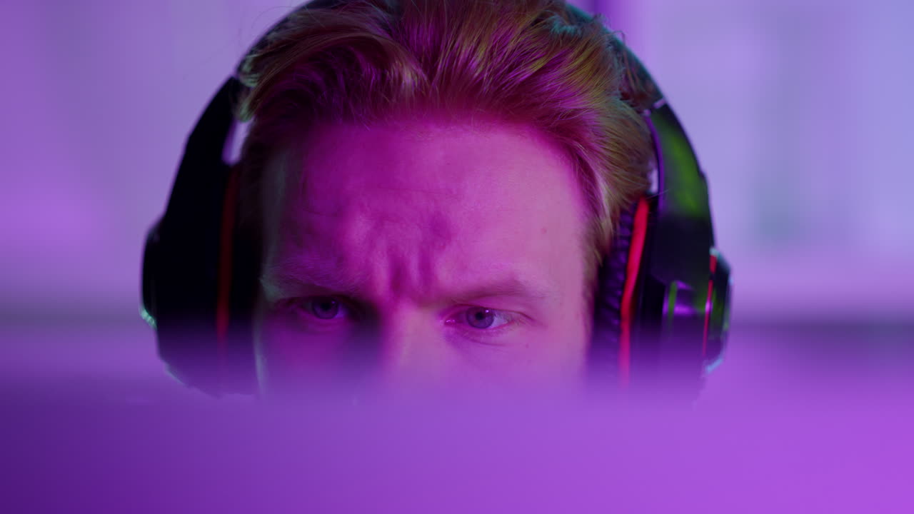 Primo piano di un uomo che gioca a giochi cyber online con le cuffie. Streamer di arcade concentrato.