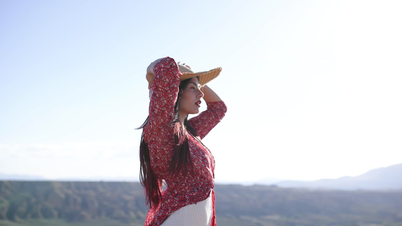 A woman in a red dress and hat enjoying the scenic outdoors